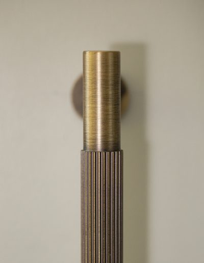 Close-up of vertical fluted brass cabinet handle against painted wall