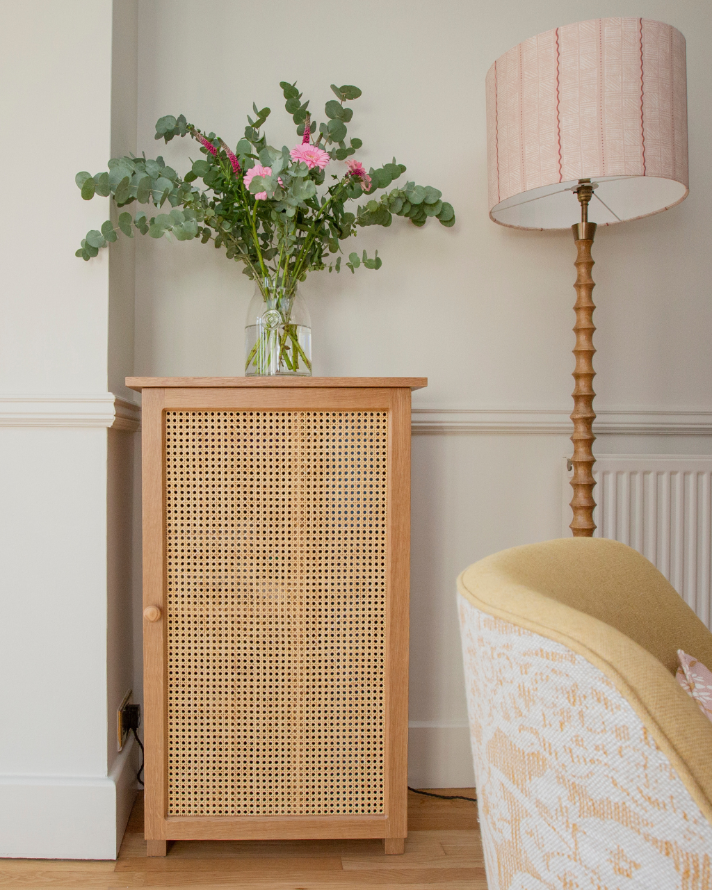 Bespoke oak cabinet with rattan front, styled with flowers and lighting
