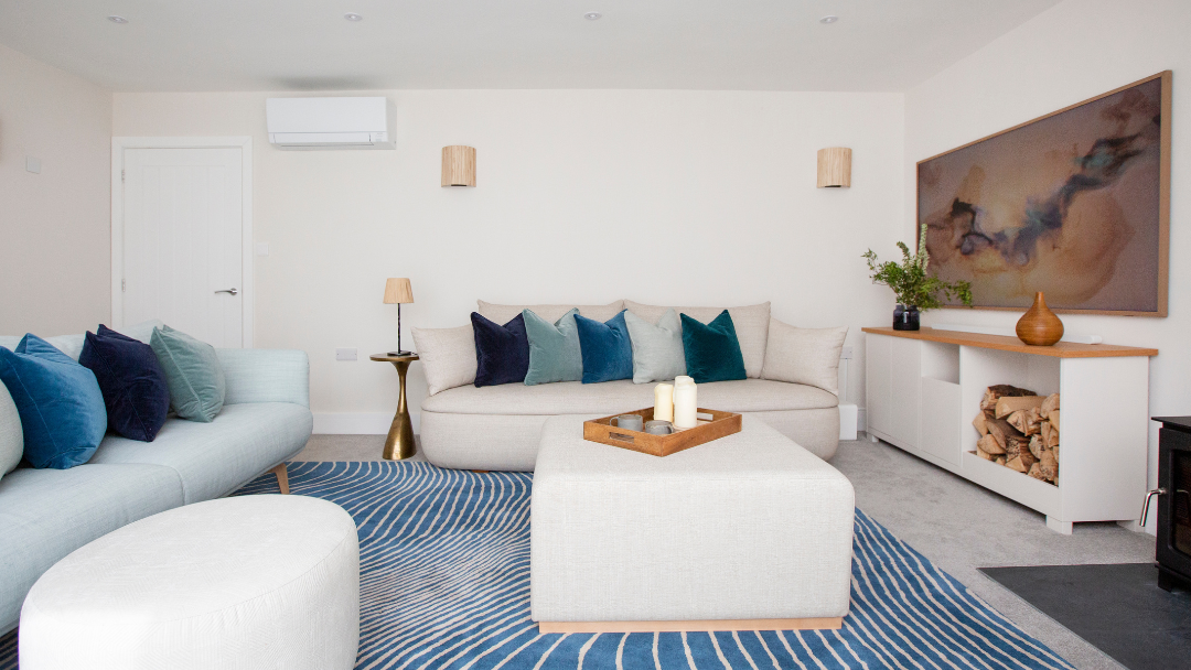 After : Completed sitting room with curved sofas, abstract art and blue accent cushions in a modern Cotswold home