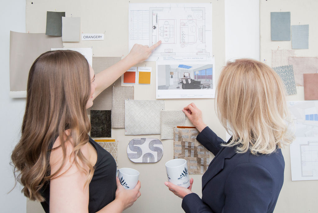 Interior Designers Reviewing Layout Plans and Material Samples Interior designers reviewing layout plans and material samples on a wall, discussing finishes and spatial planning for a residential project.