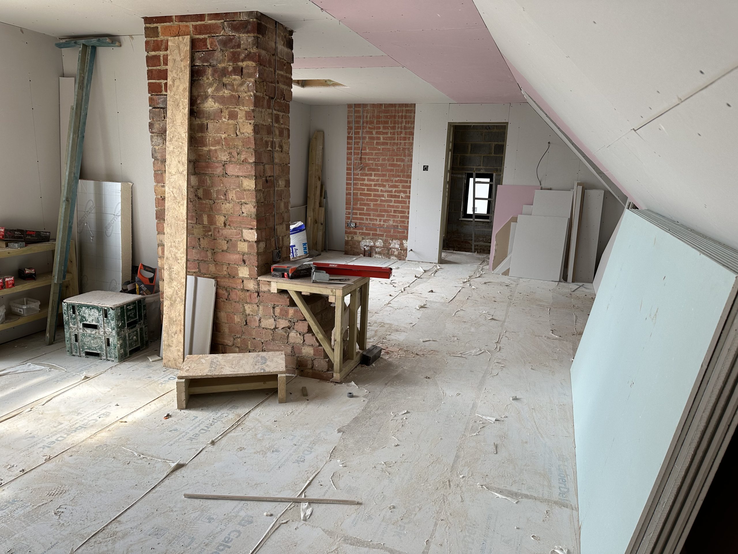 Unfinished loft renovation with exposed brickwork and materials before interior design planning is finalised