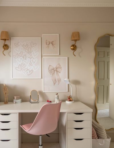 Tweenager's desk area with gallery wall, brass wall lights, wavy gold mirror, pink desk chair and painted fitted wardrobe, designed by The House Ministry.