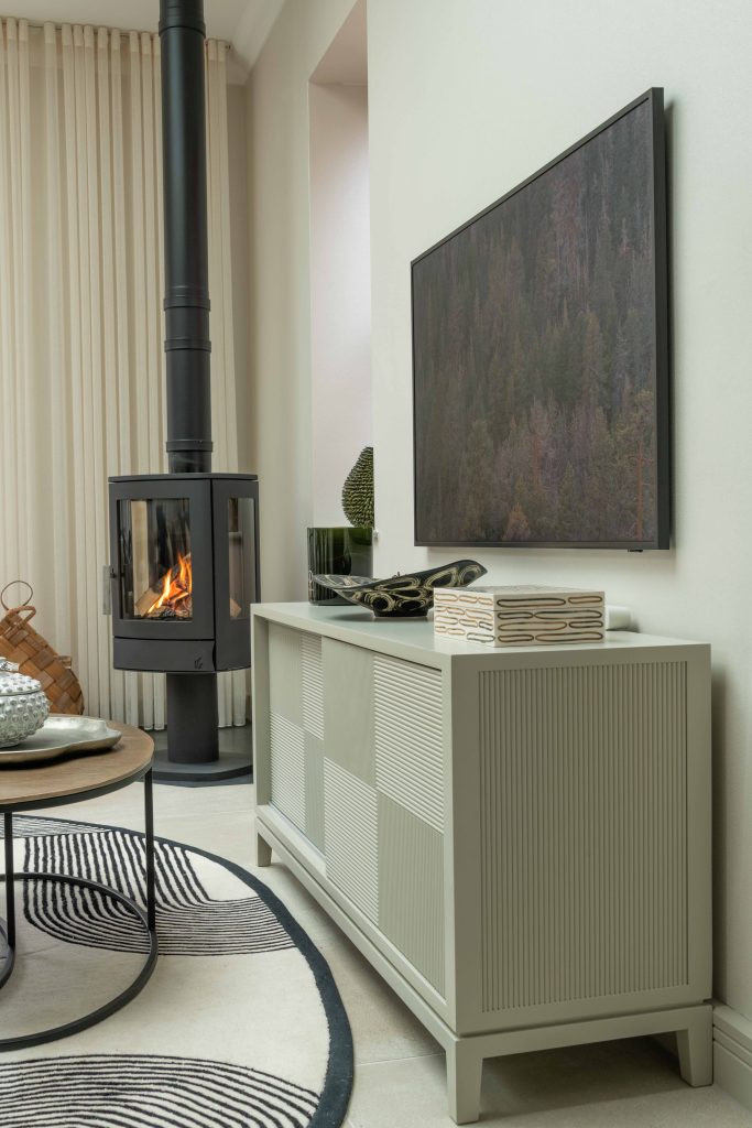 Contemporary living room with bespoke sideboard, woodburner and artwork, designed by The House Ministry in the Cotswolds