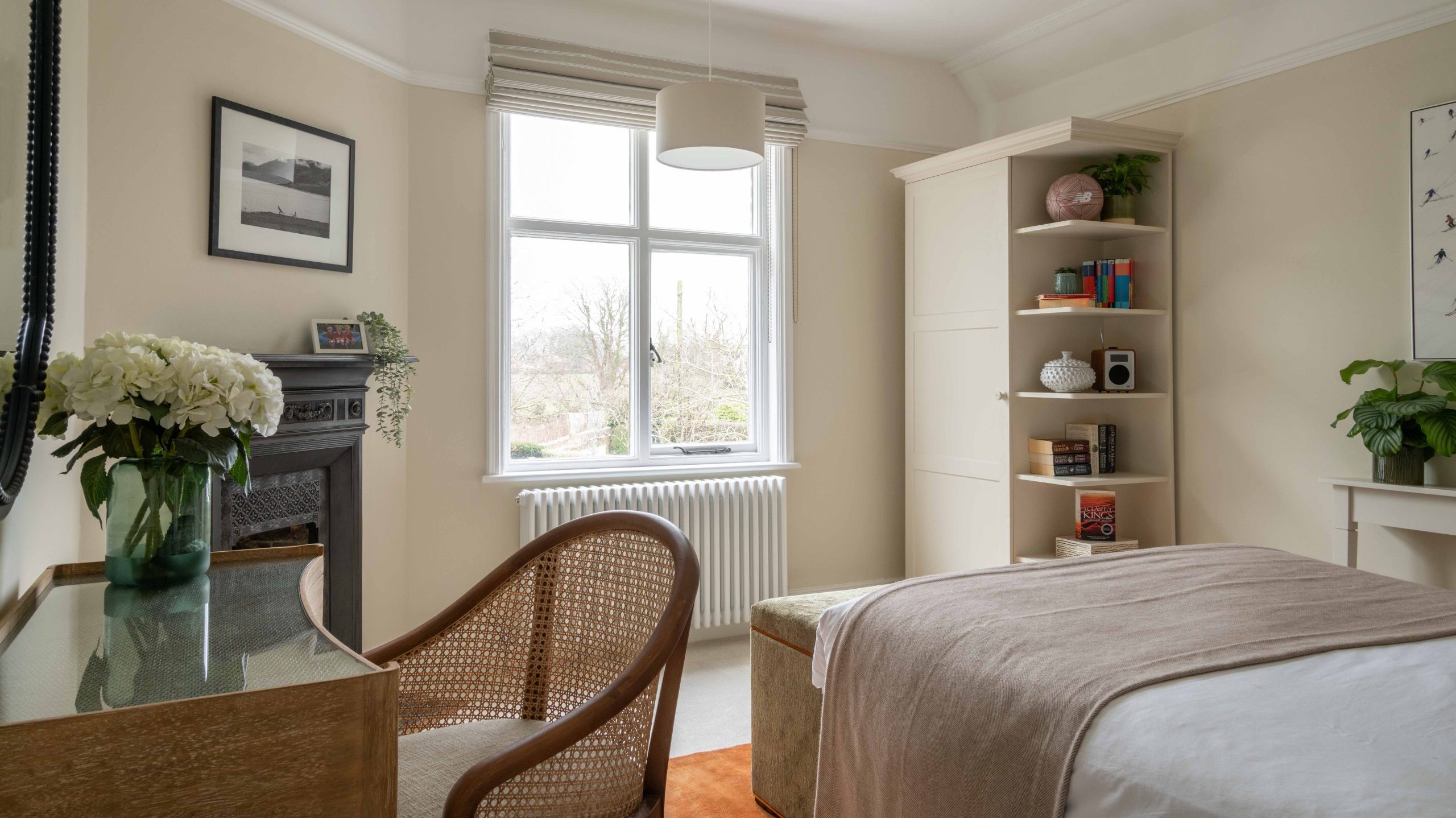 Bedroom with Bespoke Wardrobe and Open Display Shelving | The House Ministry Bedroom with original fireplace, cane dressing chair, oak dressing table, bespoke wardrobe with open display shelving and garden view, designed by The House Ministry.