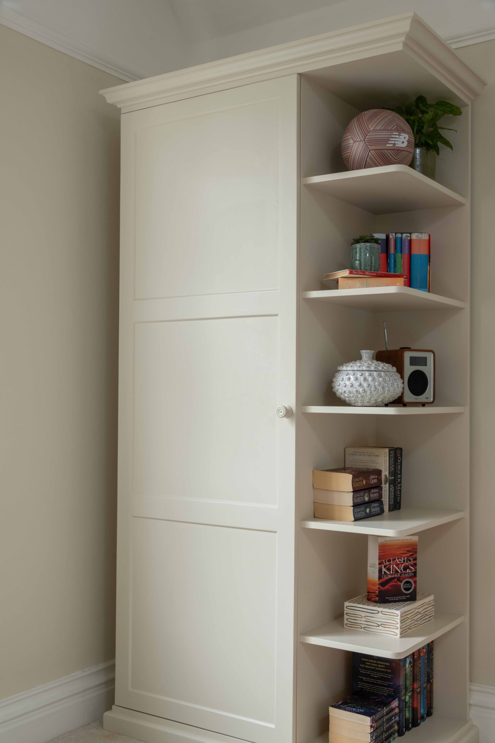 Bespoke Wardrobe with Open Display Shelving | The House Ministry Bespoke wardrobe with panelled door and open display shelving, dressed with books and ornaments, designed by The House Ministry.