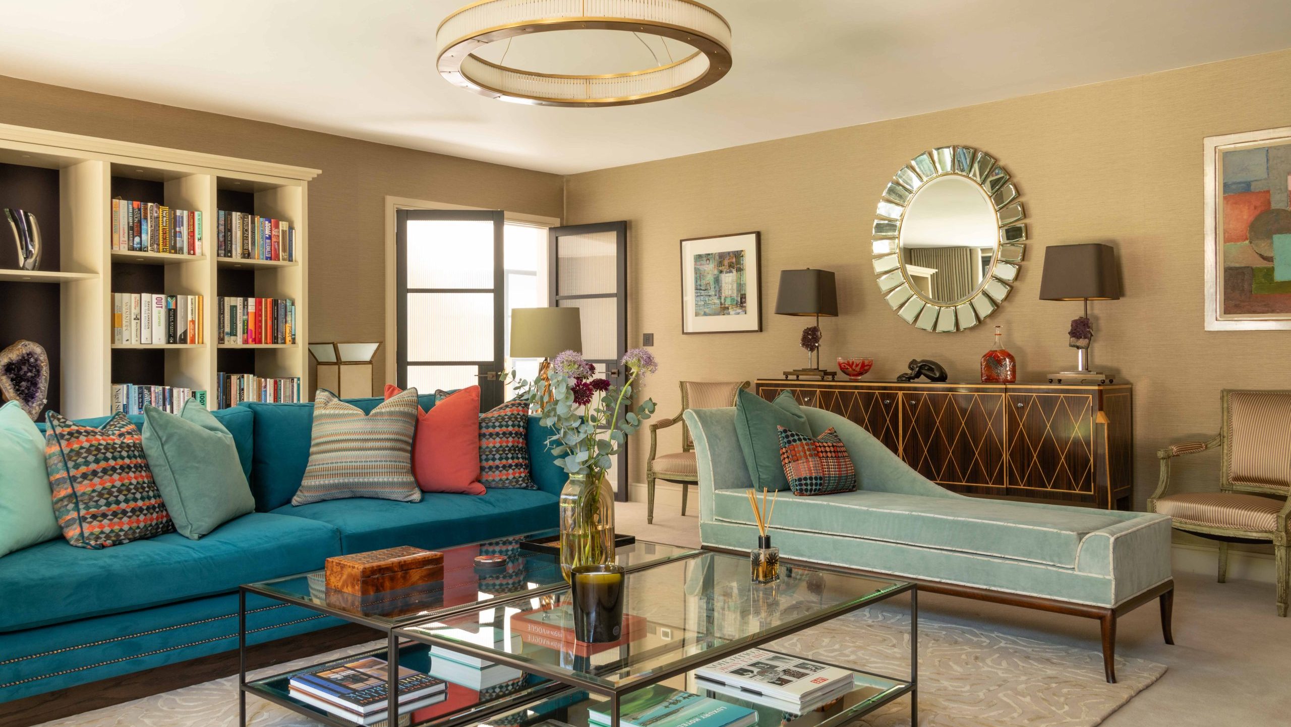 Full Living Room View | The House Ministry Living room with teal sofa, sage chaise longue, statement ring pendant light and existing sunburst mirror above a marquetry sideboard